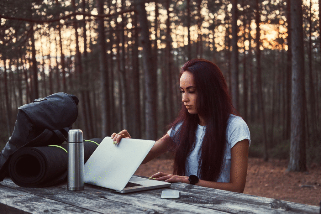 (hipster-girl-opening-laptop-working-wooden-bench-while-having-break-beautiful-autumn-forest_Image by fxquadro on Freepik)